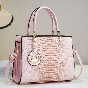 Detail of pink faux crocodile leather handbag with metal swan charm and double handles