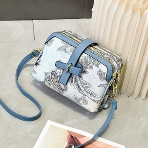 Vue détaillée du sac bandoulière à motif paisley avec trois zips et détails dorés