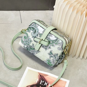 Détail du sac bandoulière cachemire vert clair avec trois compartiments zippés et dorures