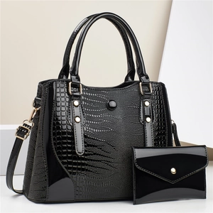 Macro detail of the glossy lizard embossed texture and golden metal buckle on black tote