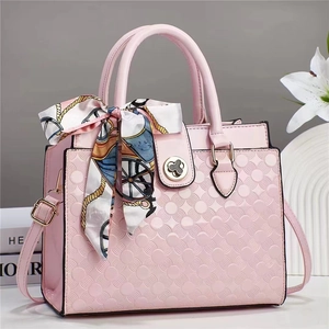 Détail d'un sac à main rose texturé avec foulard en soie décoratif et fermoir trèfle chic