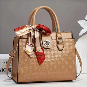Détail du sac à main en cuir verni gaufré avec fermoir floral et foulard en soie chic