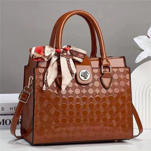 Détail du sac en cuir verni marron montrant la texture gaufrée et le décor en soie