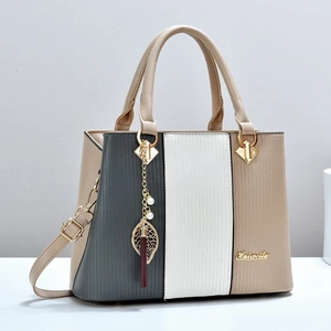 Three-color patchwork leather tote bag with vertical embossed texture and leaf pendant