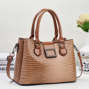 Détail du sac à main marron à motif lézard avec fermoir métallique et anses lisses