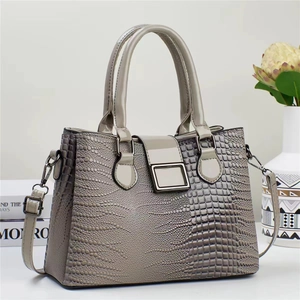 Détail d'un sac à main gris texture lézard avec boucle métallique et double poignée
