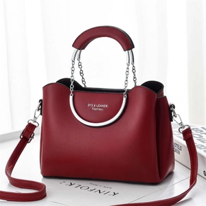 Close-up of burgundy leather crossbody bag with silver round handles and chain link detail