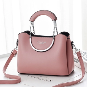 Detail of pink leather handbag with semi-circular metal handle and chain link design