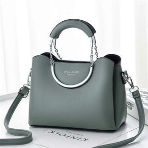 Detail view of sage green leather bag with chain handle and detachable shoulder strap