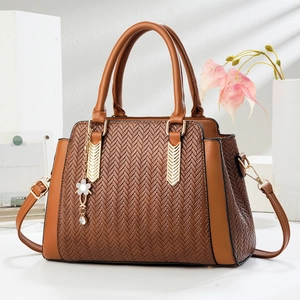 Brown woven texture handbag with gold hardware and white floral charm on white desk