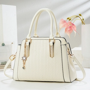 Elegant cream tote bag with V-shaped woven texture and floral charm on a white stand