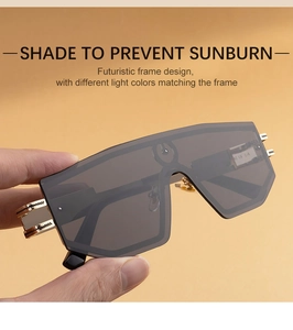 Detail of futuristic one-piece sunglasses with dark grey lens and golden metal temples
