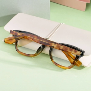 Détail de lunettes de soleil carrées écaillées sur un étui de rangement en cuir crème