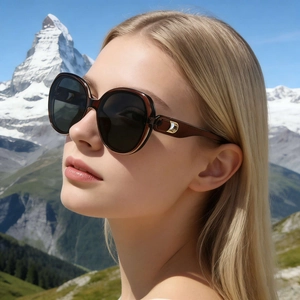 Fashionable oversized square nylon sunglasses with gold accents worn against snowy mountains