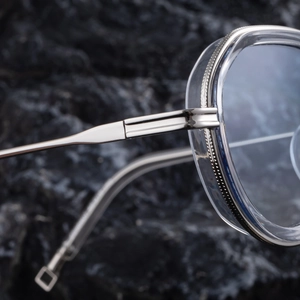 Close-up of silver metal hinges and gear-shaped metal trim on clear oval sunglasses