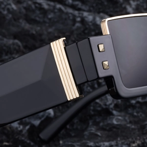Macro shot of durable metal hinges with gold accents on black square sunglasses frame