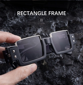 Detail of black rectangle sunglasses with silver metal studs on a rugged stone background
