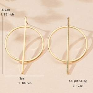Golden geometric hoop earrings with vertical bars on a textured stone background