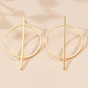 Close-up of golden geometric earrings with vertical bar and circle in natural light