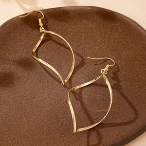 Boucles d'oreilles pendantes géométriques dorées présentées sur un plateau décoratif