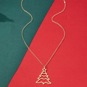 Collier avec pendentif sapin de Noël doré posé sur un fond festif rouge et vert