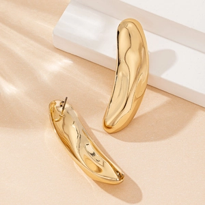 Elegant gold irregular curved stud earrings on a minimalist display with soft leaf shadows