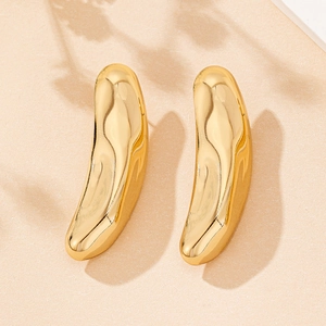 Detailed view of irregular gold fluid earrings with a polished mirror finish on beige surface