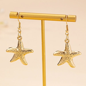Boucles d'oreilles pendantes étoile de mer dorées avec texture sur présentoir à bijoux