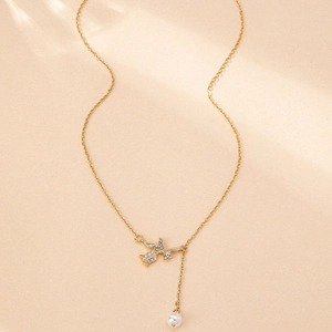 Detailed view of the gold-tone necklace featuring a diamond rose and white pearl charm