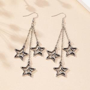 Macro detail of retro silver star tassel earrings with delicate long metal chains