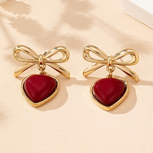 Close-up of elegant bow earrings with heart pendants in vintage red and gold finish