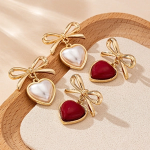 Elegant gold bow heart earrings set in pearl white and deep red finishes for daily wear