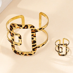 Vue détaillée d'une parure de bijoux léopard dorée avec bracelet ouvert et bague