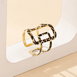Modern geometric leopard print hollow cuff bracelet in gold finish on stone display