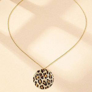 Détail du pendentif rond motif léopard sur une chaîne fine dorée élégante