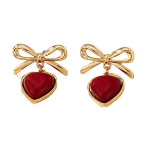 Elegant gold bow earrings with deep red heart pendants on a clean white background