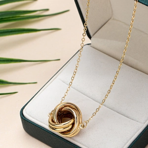 Elegant gold interlocking triple ring pendant necklace on a jewelry gift box