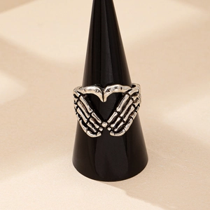 Bague vintage punk mains de squelette cœur sur un support à bijoux noir en argent vieilli