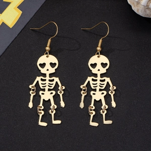 Macro detail of golden skeleton earrings with heart-shaped eyes and movable joints