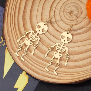 Halloween articulated golden skeleton drop earrings with heart eyes on wooden tray