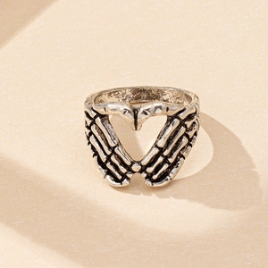 Détail macro d'une bague gothique argentée avec mains de squelette formant un motif cœur