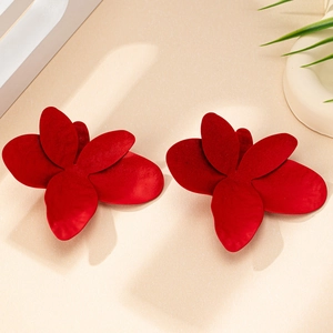 Gros plan de boucles d'oreilles fleurs rouges avec finition mate et pétales superposés