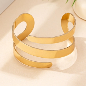 Close-up of golden triple-layer spiral cuff bracelet with polished minimalist finish