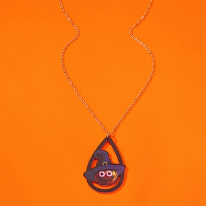 Macro shot of Halloween pumpkin pendant with witch hat on orange creative background
