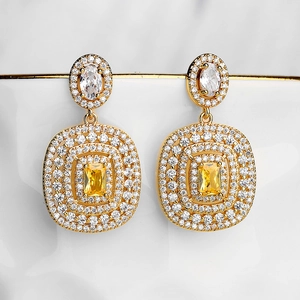 Detail of gold-plated tassel earrings with yellow rectangular zircon and sparkling stones