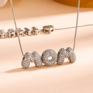 Gros plan du collier chaîne à mailles argentées avec pendentif lettre MOM pavé de cristaux