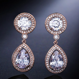 Macro detail of rose gold earrings with pear-cut halo zircon stones and tassel accents