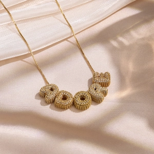 Gros plan du collier doré ADORE avec lettres serties de cristaux sur fond de soie