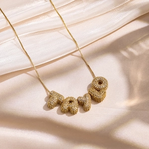 Vue macro du collier doré TAYLO avec cristaux pavés sur satin couleur champagne