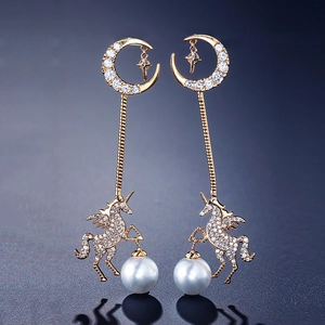 Detailed view of gold unicorn earrings with crescent moon, zircon and large pearl drop